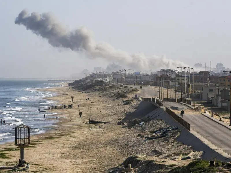 Coastal city with smoke rising in distance.