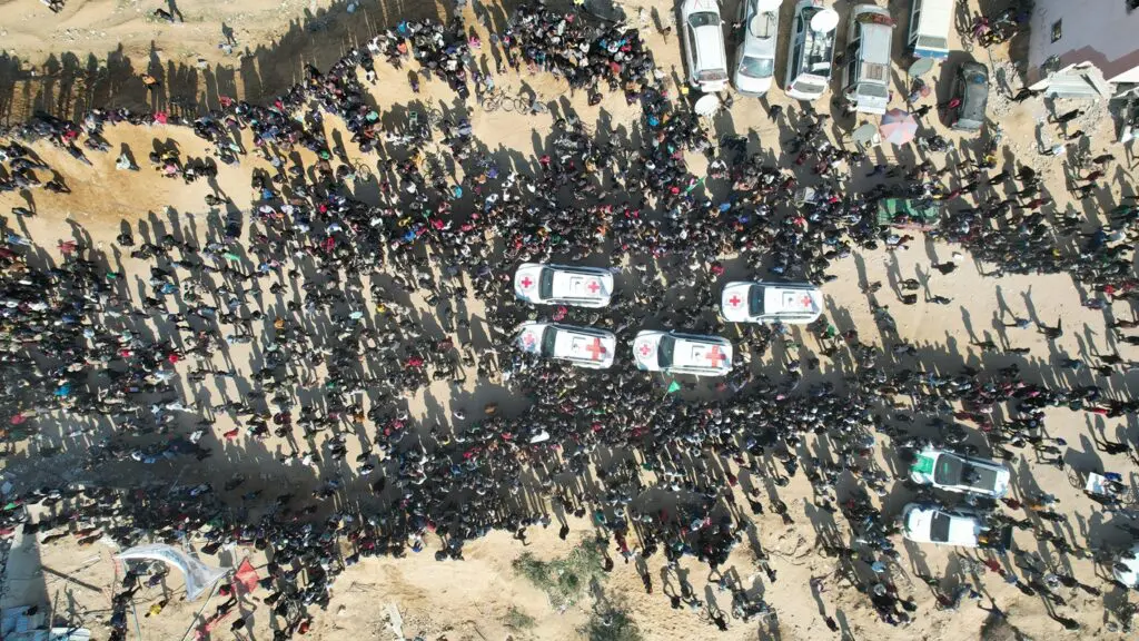Aerial view of crowd surrounding ambulances.