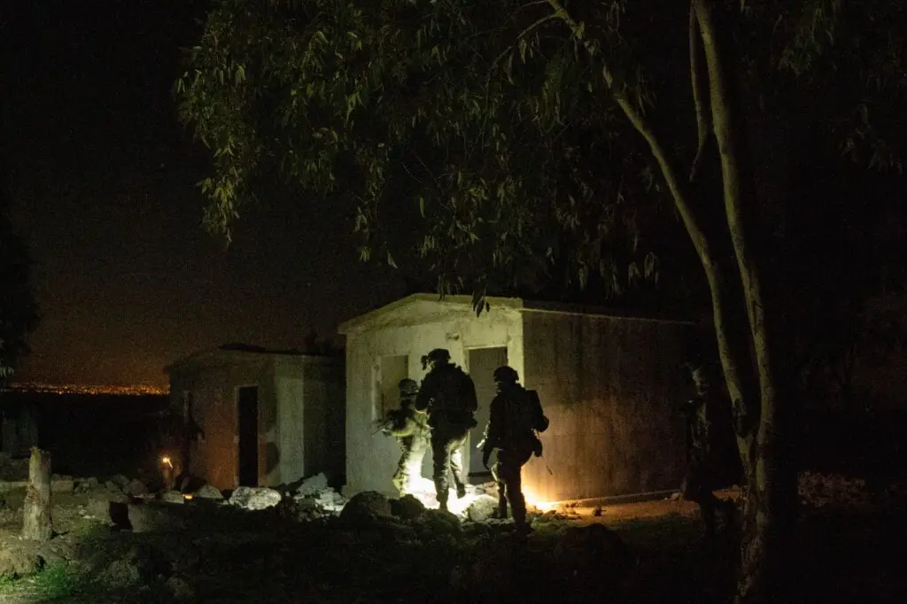 Soldiers conducting night operation near building