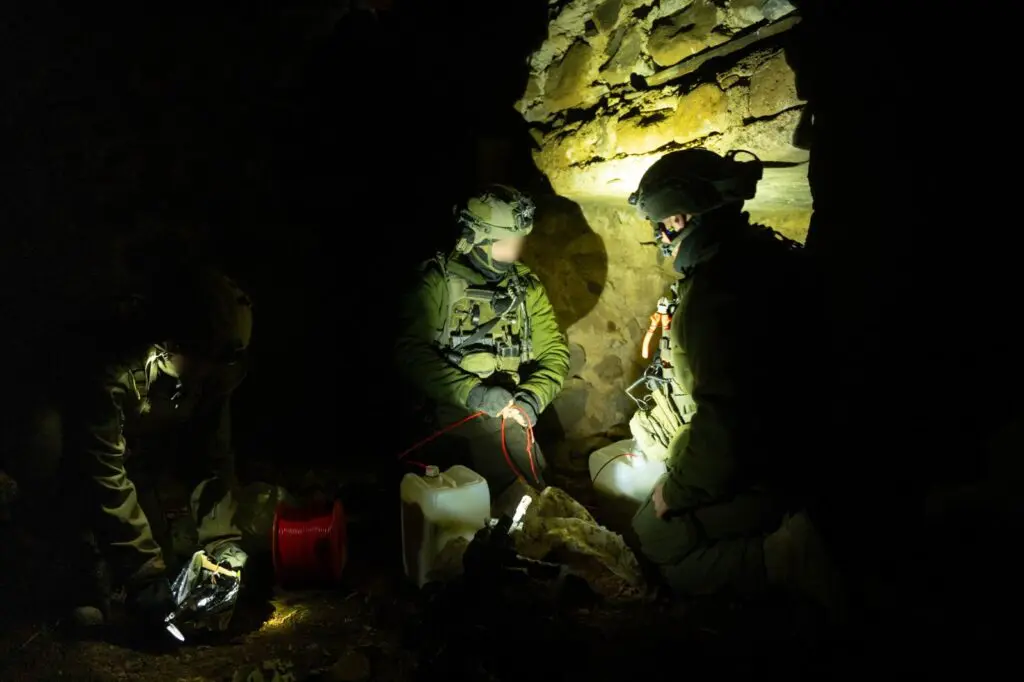 Soldiers in dark area setting up equipment.