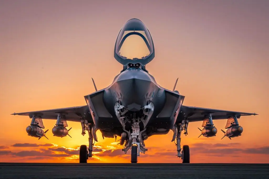 Fighter jet at sunset with armaments.