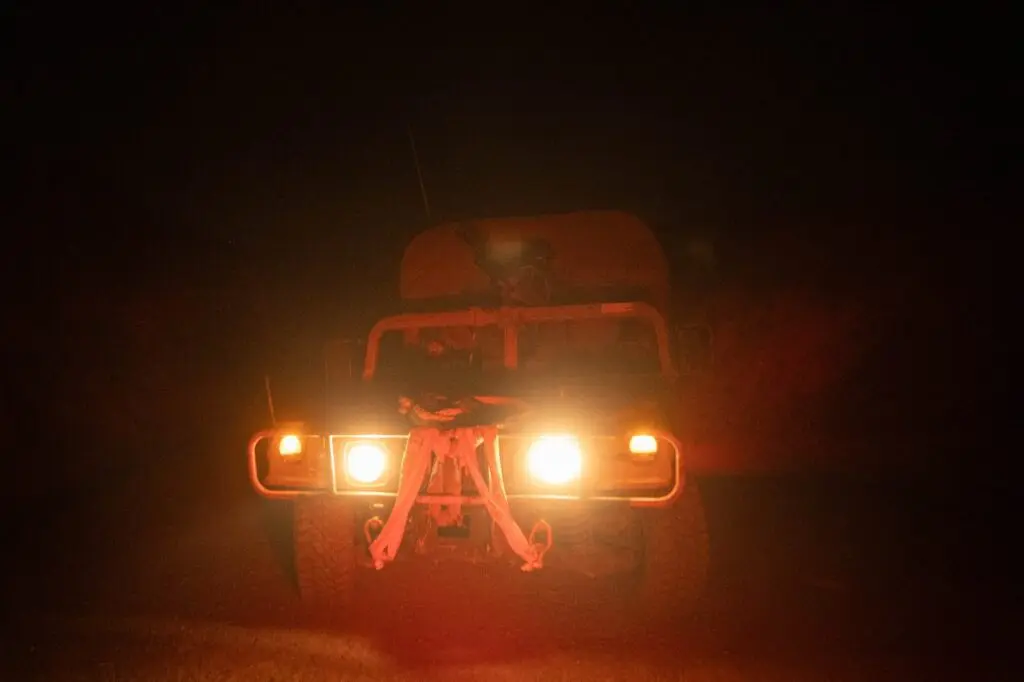 Military truck with headlights on during night