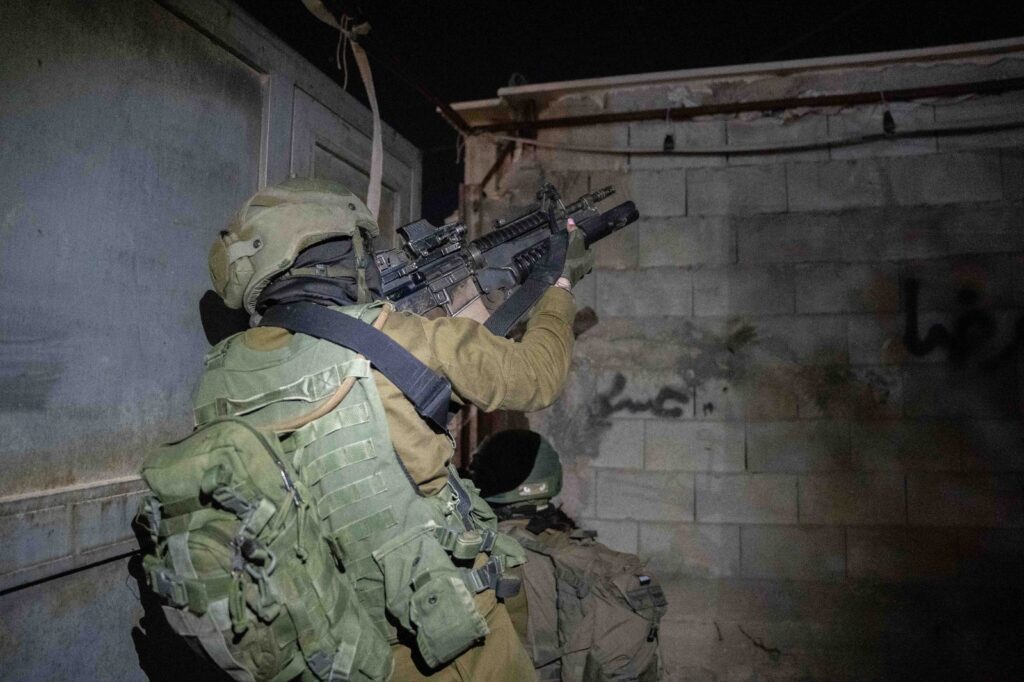 Soldier aiming rifle at night in urban area.