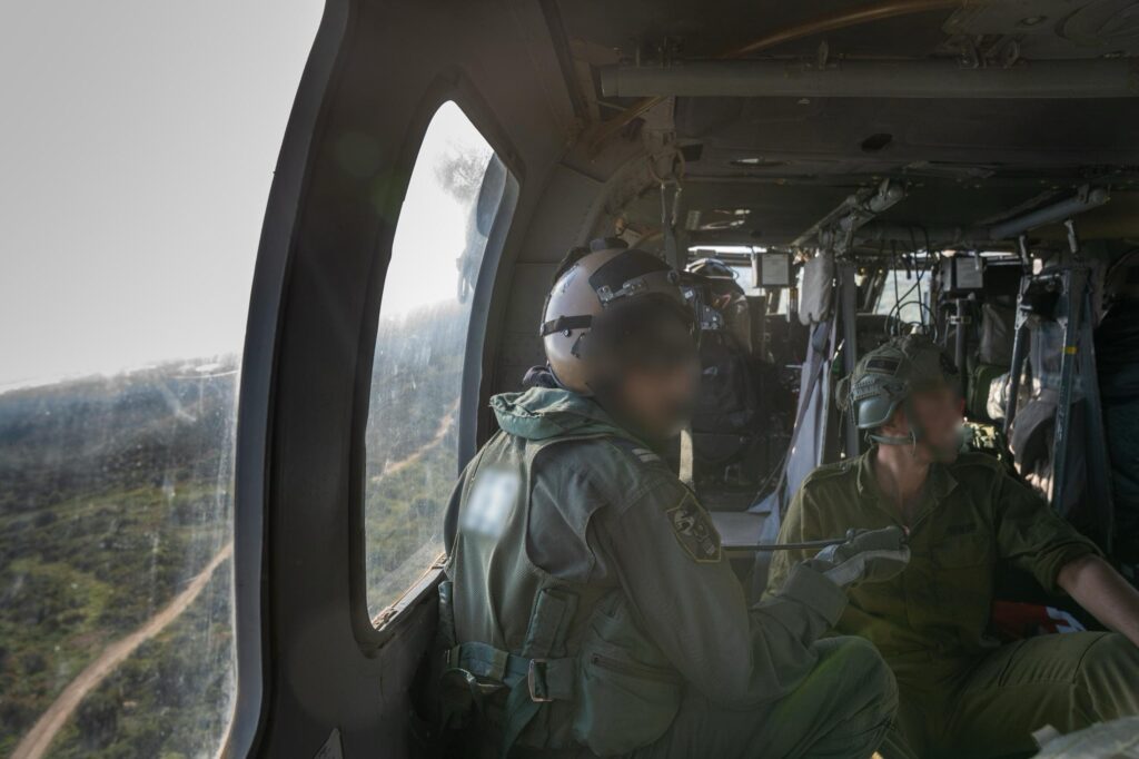 Military personnel inside a helicopter in flight.