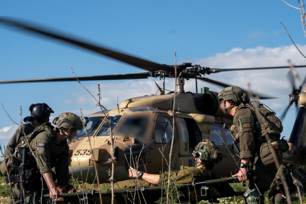 Soldiers evacuating person to helicopter in field.