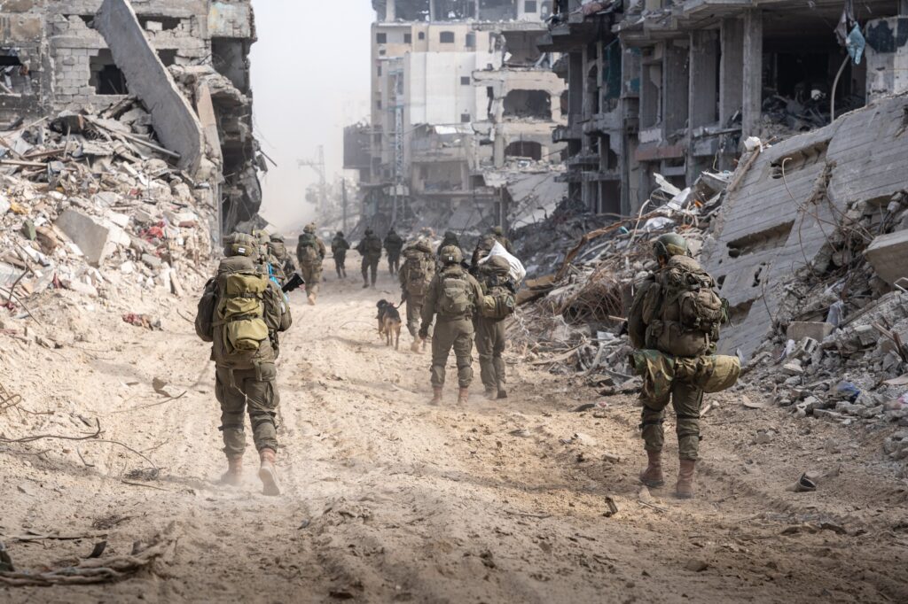 Soldiers walking through city ruins, debris everywhere.