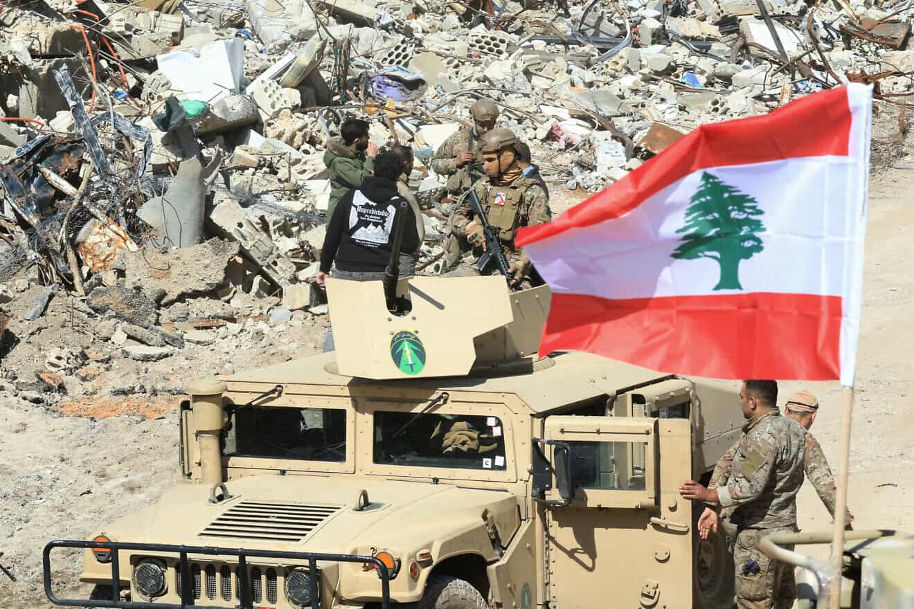 Soldiers on armored vehicle near rubble, Lebanese flag visible.