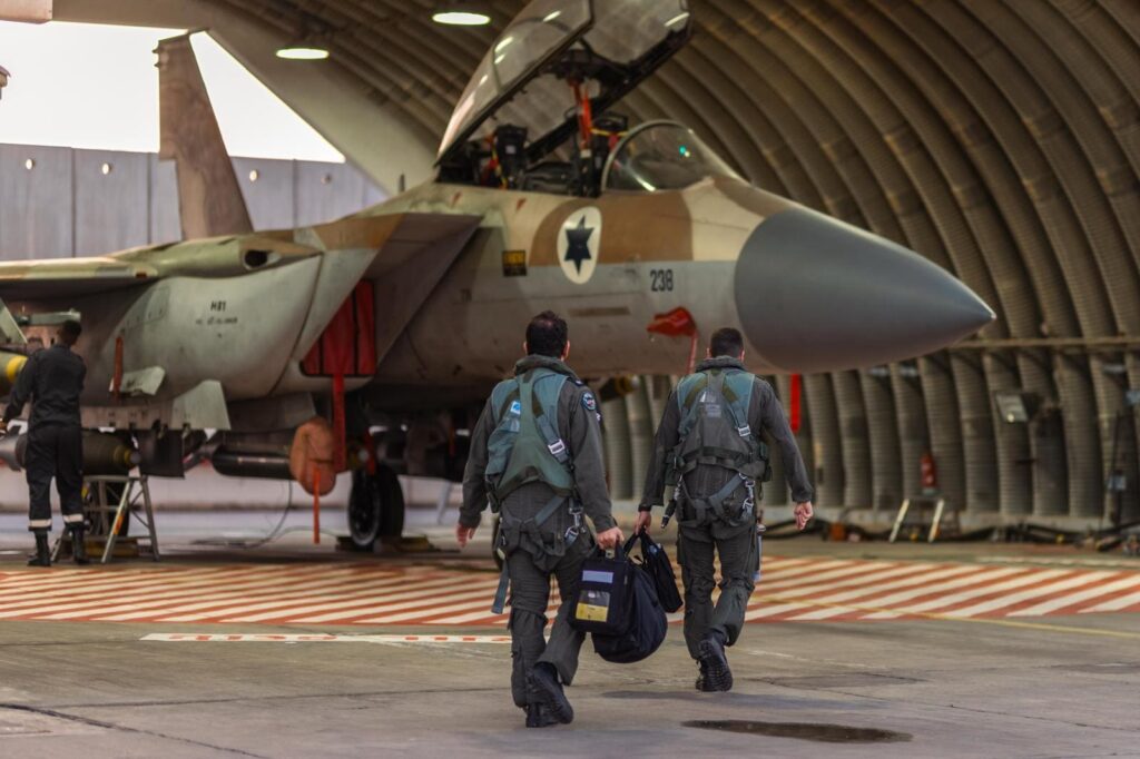 Pilots walking towards military jet in hangar