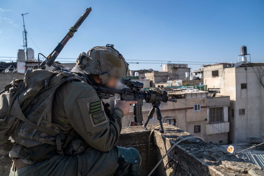 Soldier aiming rifle on rooftop in urban area.