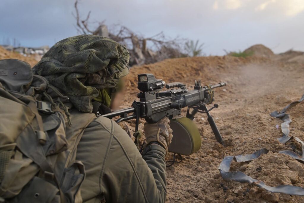 Soldier aiming rifle in camouflage gear.