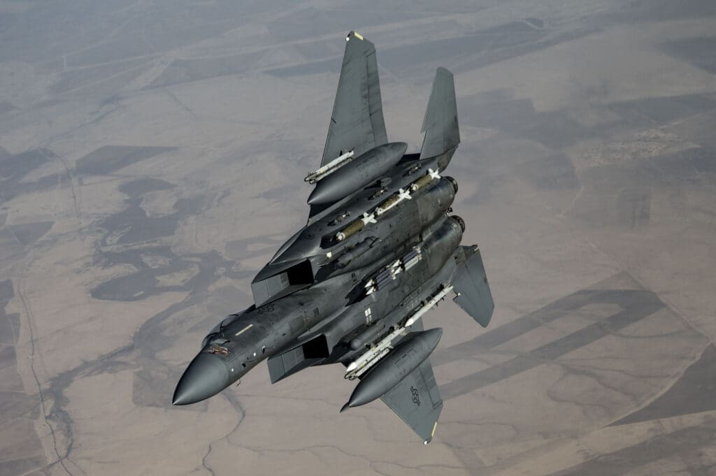 Military jet flying over desert landscape.